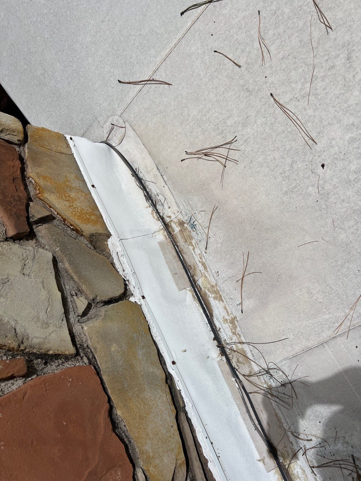 Flat roof seam along a stone parapet