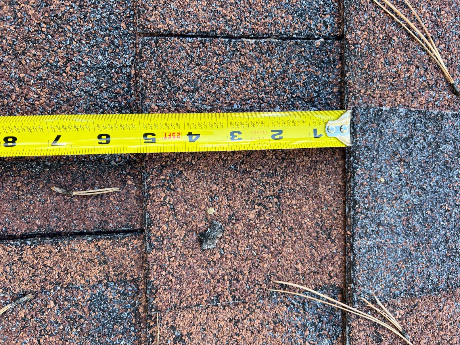 Damaged shingle measured with a tape for the insurance file